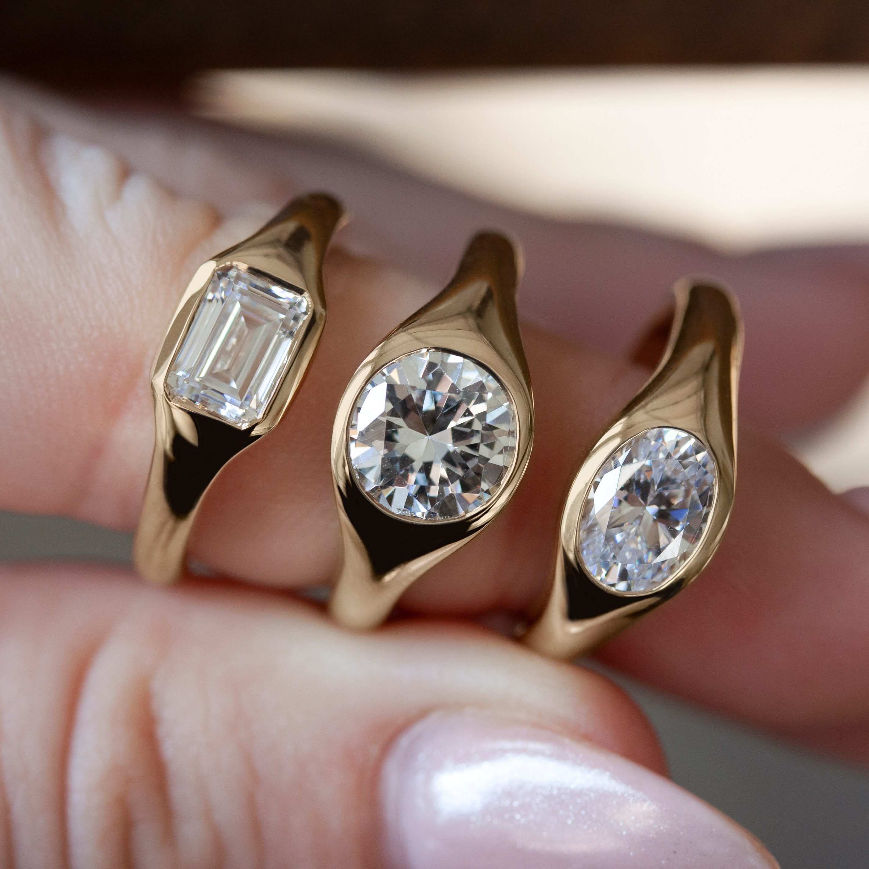 Three gold signet rings by Philadelphia's Emily Chelsea Jewelry, featuring soft curves and flush-set white diamonds.