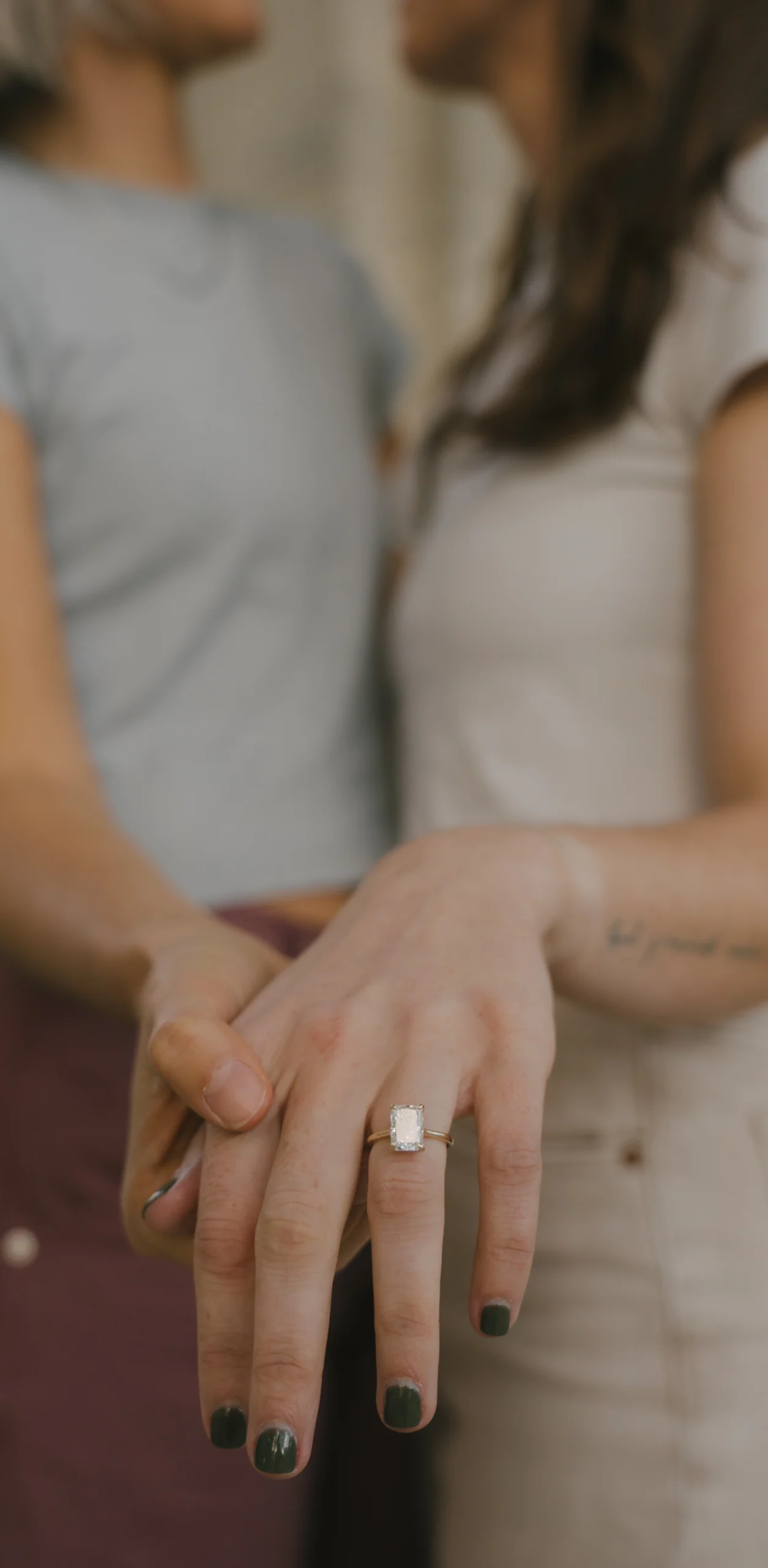 Two women embrace with a close up of their rings